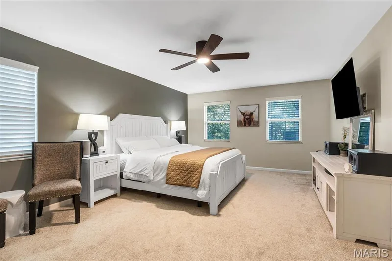 Neutral-toned interior featuring an accent wall, wall-to-wall carpeting, multiple windows with blinds, and a ceiling fan with integrated lighting — 1444 Eagle Ridge Road, Wildwood, MO 63038