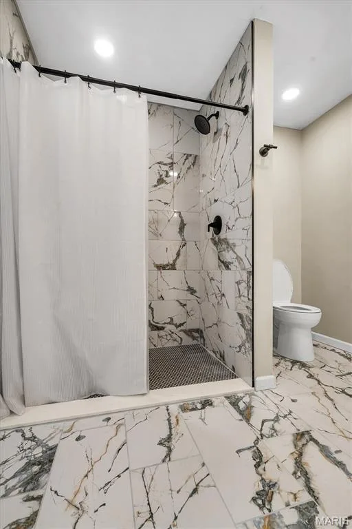 Walk-in shower featuring large-format veined tile surround, mosaic floor tile, and matte black fixtures, complemented by matching floor tile throughout — 1444 Eagle Ridge Road, Wildwood, MO 63038