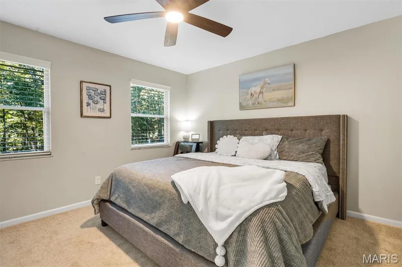 Neutral-toned room featuring wall-to-wall carpeting, dual windows, and a ceiling-mounted fan with integrated lighting — 1444 Eagle Ridge Road, Wildwood, MO 63038