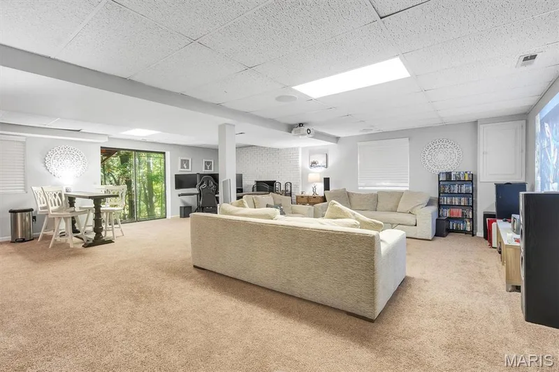 Open-concept interior featuring a drop ceiling with recessed lighting, wall-to-wall carpeting, sliding glass doors, and a structural support column — 1444 Eagle Ridge Road, Wildwood, MO 63038