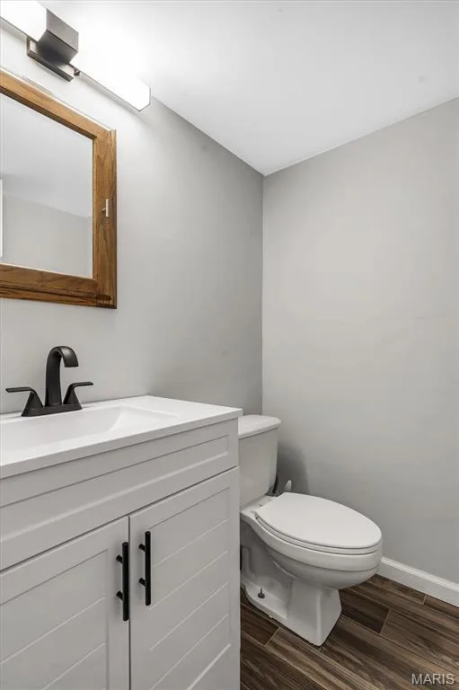 White shaker-style vanity with a rectangular sink, matte black faucet, wall-mounted wooden medicine cabinet, and wood-finish flooring — 1444 Eagle Ridge Road, Wildwood, MO 63038