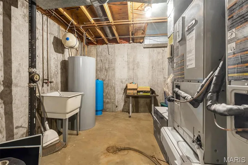 Utility area featuring a poured concrete foundation, forced-air furnace, electric water heater, pressure tank, and utility sink — 1444 Eagle Ridge Road, Wildwood, MO 63038