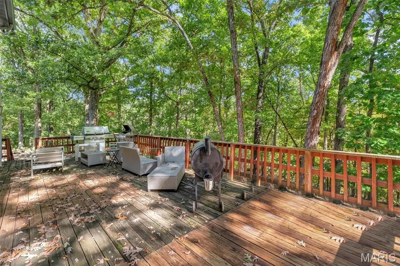 Elevated wood deck featuring vertical balustrade railings and surrounding mature tree canopy — 1444 Eagle Ridge Road, Wildwood, MO 63038