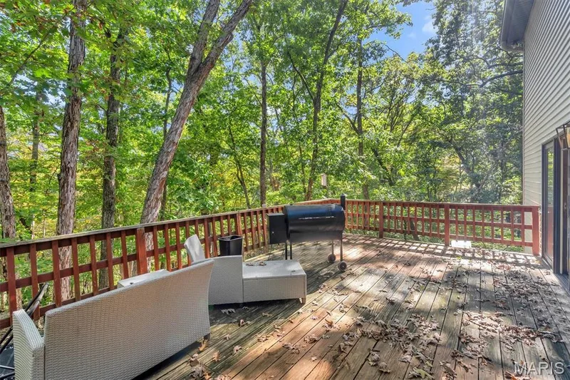 Elevated wood deck featuring vertical baluster railings and direct access to a heavily wooded tree line — 1444 Eagle Ridge Road, Wildwood, MO 63038