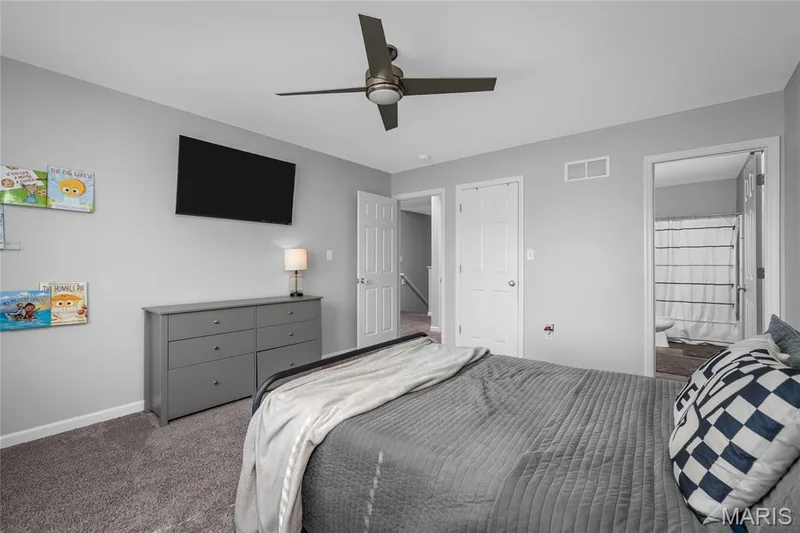 Main floor primary suite - Neutral gray walls complement the textured gray carpeting — 302 Creek Sound Court, Wentzville, MO 63385