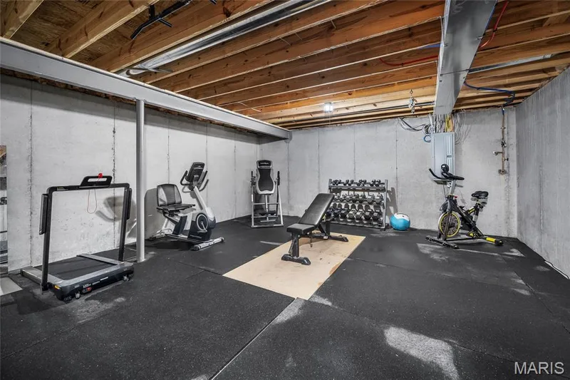 Unfinished basement space featuring concrete walls, exposed joist ceiling, and rubber flooring — 302 Creek Sound Court, Wentzville, MO 63385