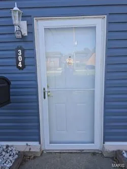 Blue vinyl siding with white trim, new door and storm door with a coach light sconce porch light...NO STEP entry! — 304 W Pitman Street, O'Fallon, MO 63366