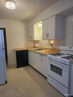 Kitchen featuring white cabinetry, light wood-finish countertops, stainless steel sink, a gas range, and a dishwasher — 304 W Pitman Street, O'Fallon, MO 63366