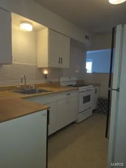 Kitchen featuring light wood-finish countertops, white cabinetry, a double basin stainless steel sink, and a white oven/range — 304 W Pitman Street, O'Fallon, MO 63366