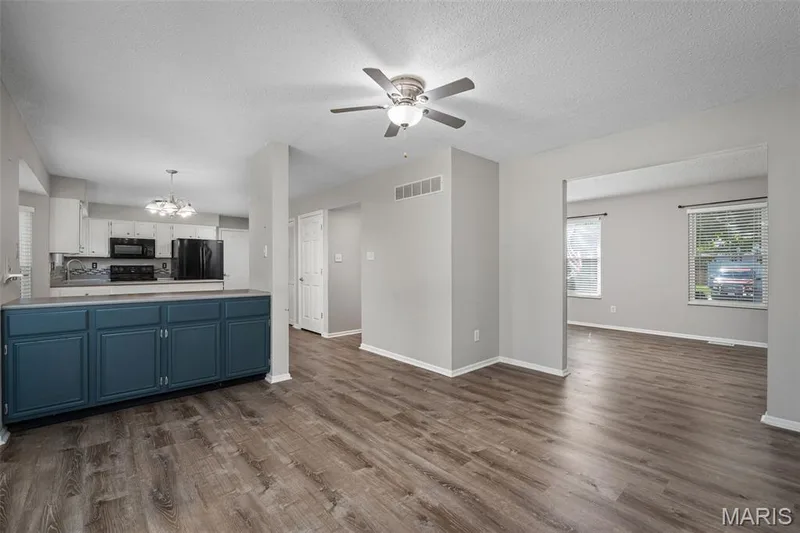 Kitchen with white upper cabinetry and dark lower cabinetry, black appliances, and a ceiling fan with integrated lighting — 445 Lantana Lane, St Peters, MO 63376