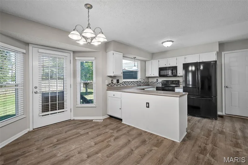 Kitchen featuring white cabinetry, black appliances, and a patterned backsplash — 445 Lantana Lane, St Peters, MO 63376