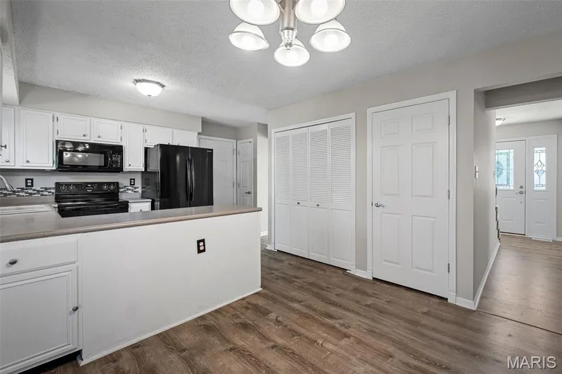 Kitchen featuring white cabinetry, black appliances, a tile backsplash, and a breakfast bar — 445 Lantana Lane, St Peters, MO 63376