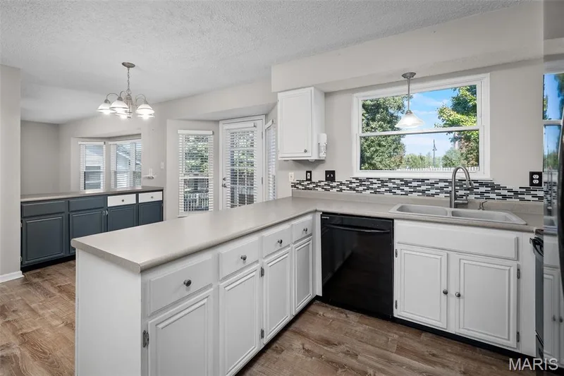 Spacious kitchen featuring an extended counter, dual-tone cabinetry, and mosaic tile backsplash. — 445 Lantana Lane, St Peters, MO 63376