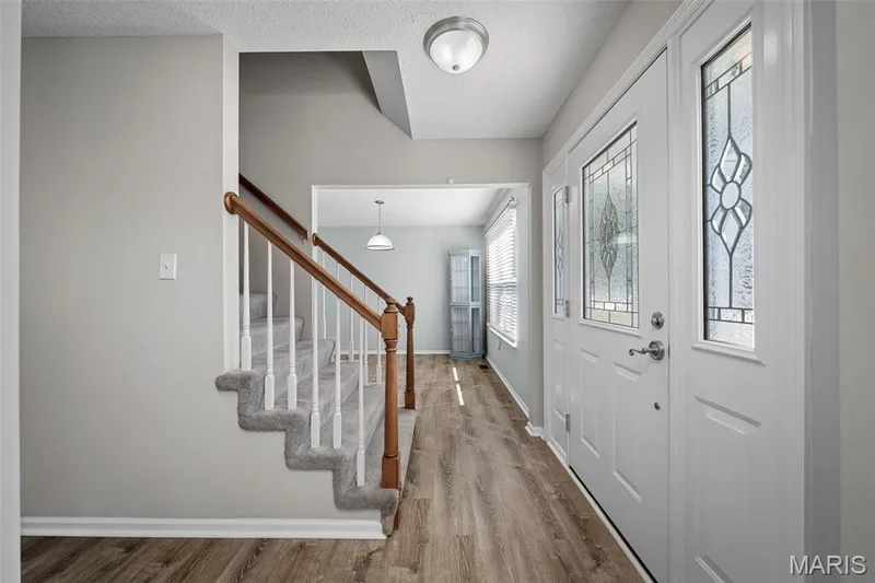Entryway featuring a staircase with carpeted treads, and a front door with decorative glass inserts — 445 Lantana Lane, St Peters, MO 63376