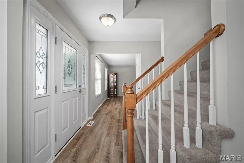 Entryway featuring a decorative glass front door, and a carpeted staircase with wood handrails — 445 Lantana Lane, St Peters, MO 63376