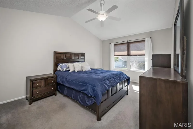 Vaulted ceiling, ceiling fan with integrated lighting, window with blinds, carpeted flooring, and neutral wall tones — 445 Lantana Lane, St Peters, MO 63376