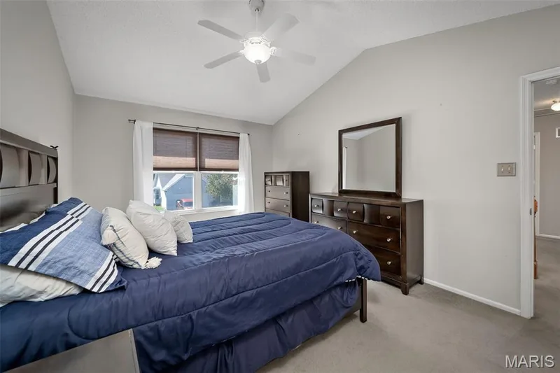 Vaulted ceiling, ceiling fan with integrated lighting, window with blinds, light gray wall paint, and gray carpeting — 445 Lantana Lane, St Peters, MO 63376