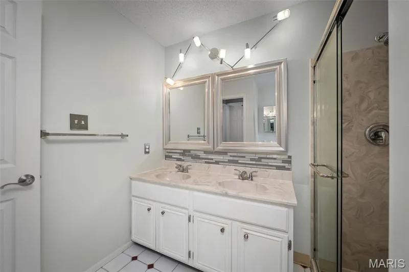 Double vanity with integrated sinks, framed mirrors, and a glass-enclosed shower — 445 Lantana Lane, St Peters, MO 63376