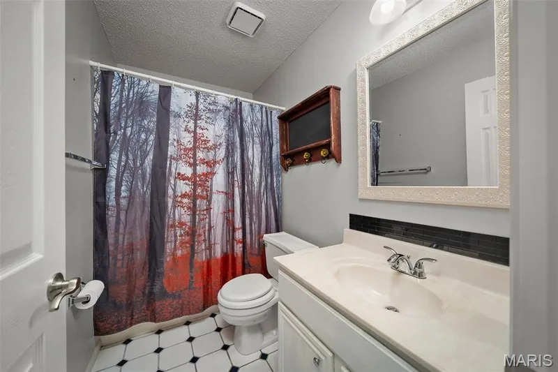White vanity with integrated sink, chrome faucet, and dark tile backsplash — 445 Lantana Lane, St Peters, MO 63376