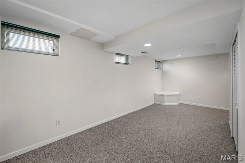 Recessed ceiling lighting, multiple windows, built-in corner feature, neutral wall paint, and textured carpeting — 445 Lantana Lane, St Peters, MO 63376