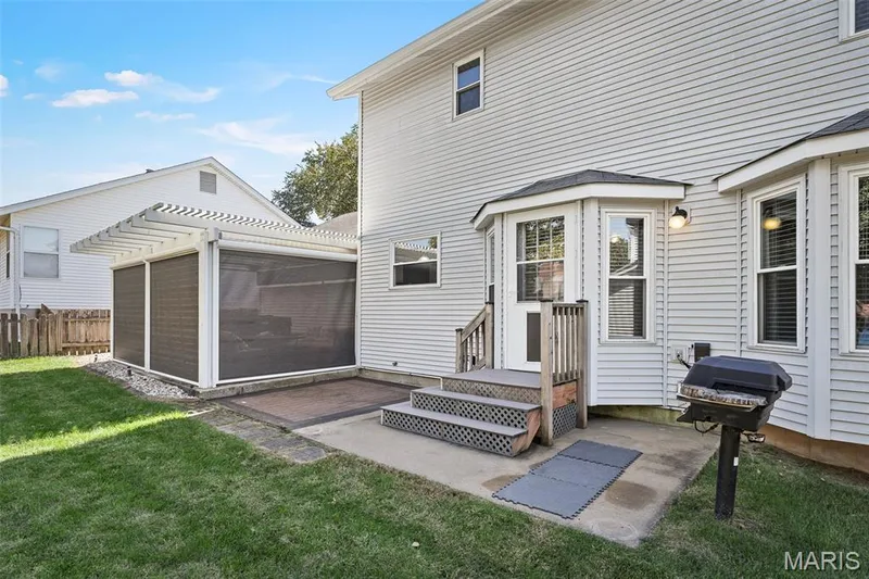 Rear exterior featuring white vinyl siding, bay windows, and a screened-in patio with a pergola — 445 Lantana Lane, St Peters, MO 63376
