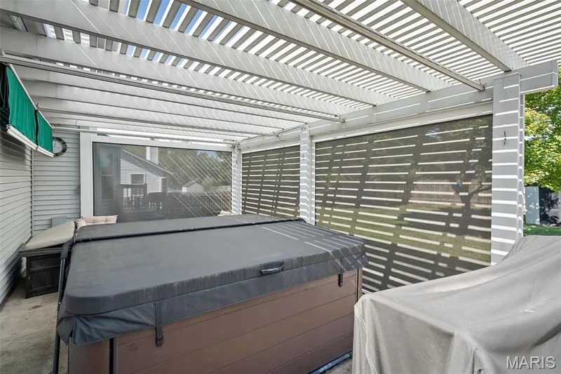 Covered outdoor patio featuring a pergola, screened enclosures, and a hot tub — 445 Lantana Lane, St Peters, MO 63376