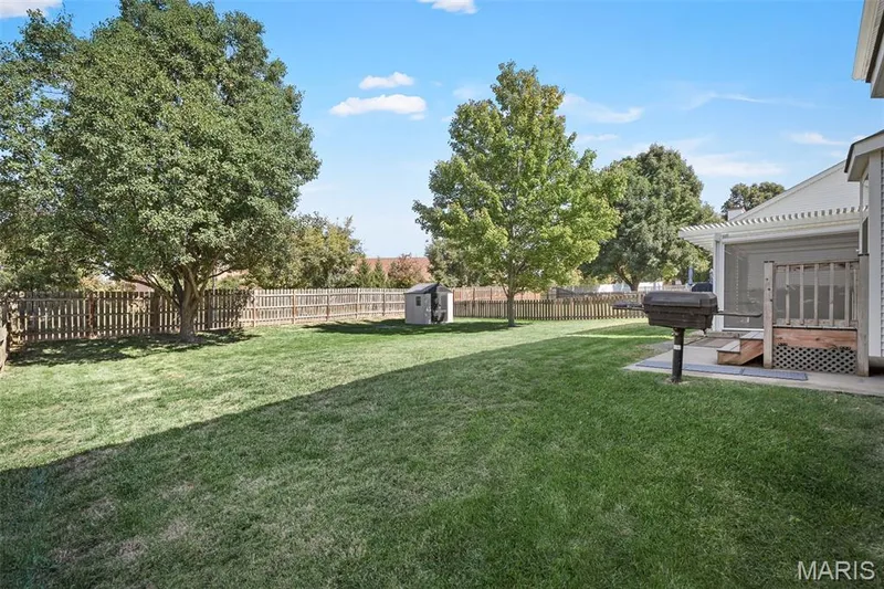 Expansive fenced yard with mature trees, screened-in porch with wood steps, and a detached storage shed — 445 Lantana Lane, St Peters, MO 63376