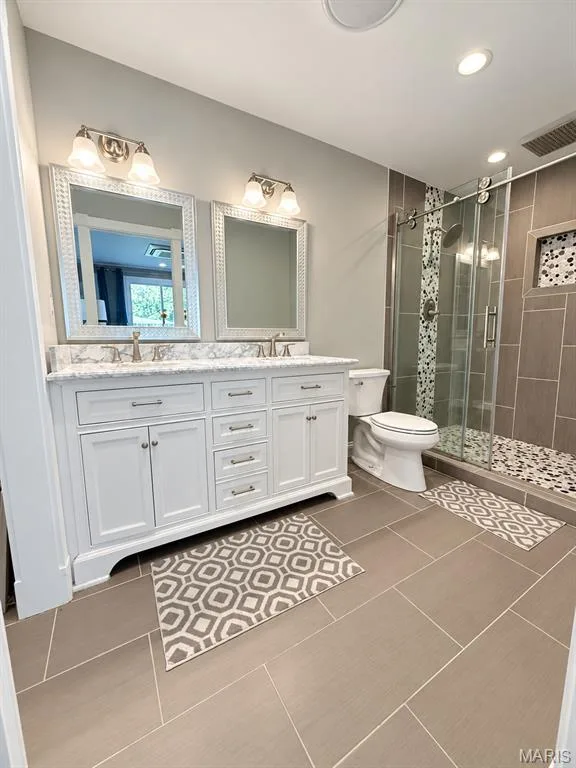 Gorgeous ensuite featuring double bowl sinks with marble like top, ceramic flooring, recessed lighting and bluetooth exhaust fan, glass shower door encased by custom tile shower with rain shower head. — 111 Valvero Drive, St Charles, MO 63304