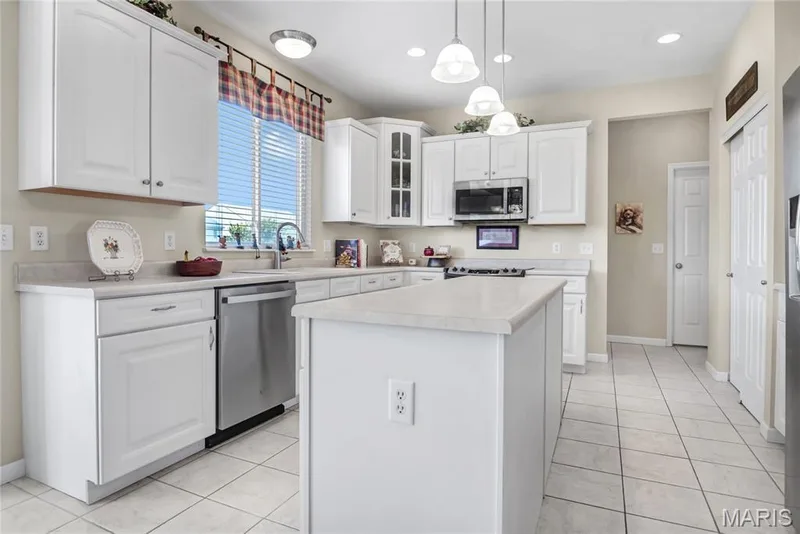 Kitchen featuring white cabinetry, center island, solid-surface countertops, stainless steel appliances, and tile flooring — 2061 Avalon Mist Circle, Dardenne Prairie, MO 63368