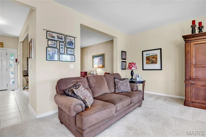 Neutral-toned interior featuring wall-to-wall carpeting, wide archways, and a multi-paned glass panel entry door — 2061 Avalon Mist Circle, Dardenne Prairie, MO 63368