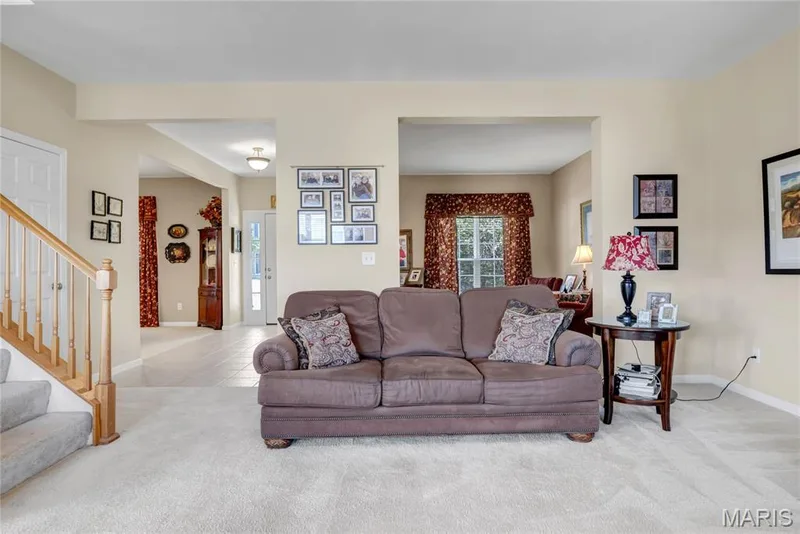 Neutral-toned interior featuring an open layout, light-colored carpeting, and a staircase with a light-finish wood handrail and square balusters — 2061 Avalon Mist Circle, Dardenne Prairie, MO 63368