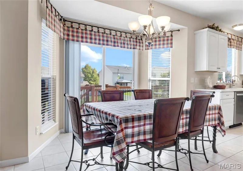 Dining space featuring tile flooring, sliding glass doors, white cabinetry, and a multi-arm chandelier — 2061 Avalon Mist Circle, Dardenne Prairie, MO 63368