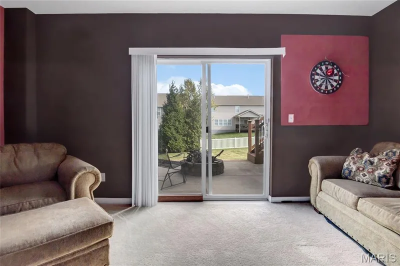 Sliding glass door with vertical blinds, providing access to a concrete patio featuring a stone-encased fire pit — 2061 Avalon Mist Circle, Dardenne Prairie, MO 63368