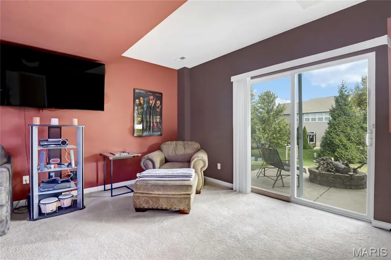 Sliding glass doors opening to a concrete patio featuring a stacked stone fire pit and manicured lawn — 2061 Avalon Mist Circle, Dardenne Prairie, MO 63368