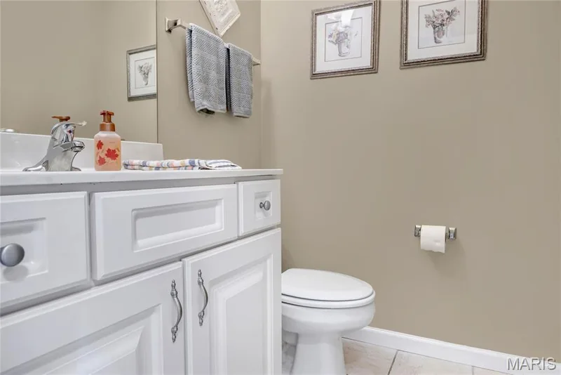 Main level half bathroom. White vanity with Shaker-style cabinetry, chrome hardware, solid-surface countertop, and an integrated basin with a chrome faucet — 2061 Avalon Mist Circle, Dardenne Prairie, MO 63368