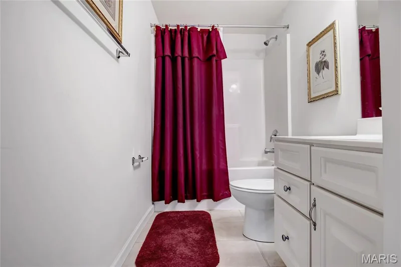 Lower level Bathroom featuring white shaker-style cabinetry, a solid-surface countertop, tiled flooring, and a combined tub and shower unit — 2061 Avalon Mist Circle, Dardenne Prairie, MO 63368