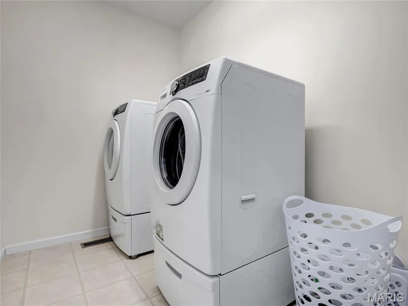2nd floor laundry, Front-loading washer and dryer set with integrated storage pedestals and neutral tile flooring — 2061 Avalon Mist Circle, Dardenne Prairie, MO 63368