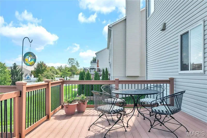 Composite deck featuring composite decking, vertical metal balusters, and a wooden handrail, with light-colored horizontal siding on the exterior — 2061 Avalon Mist Circle, Dardenne Prairie, MO 63368