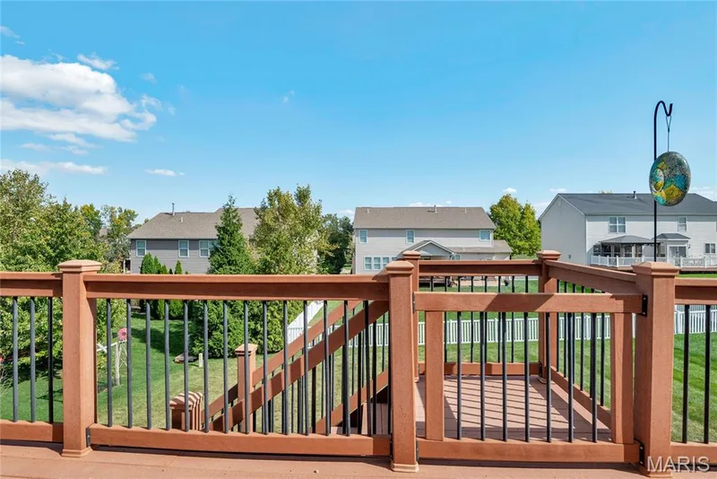 Composite wood-tone deck featuring black metal balusters, a locking gate, and a staircase leading to the rear grounds — 2061 Avalon Mist Circle, Dardenne Prairie, MO 63368