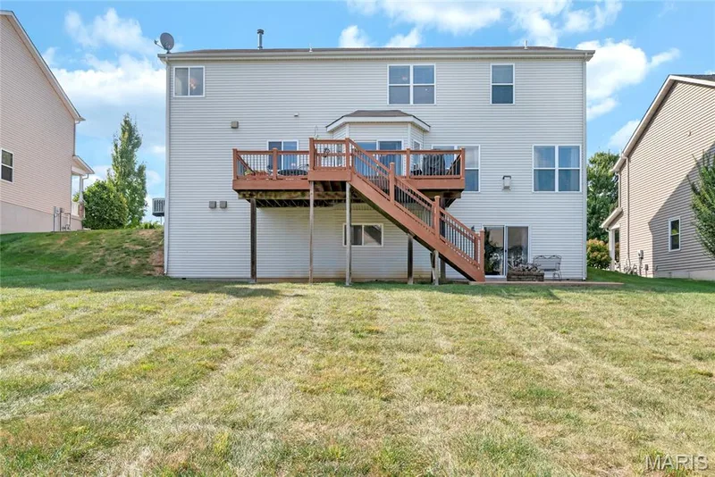 Rear exterior featuring light-toned siding, a raised wood deck with stair access, and an expansive lawn — 2061 Avalon Mist Circle, Dardenne Prairie, MO 63368