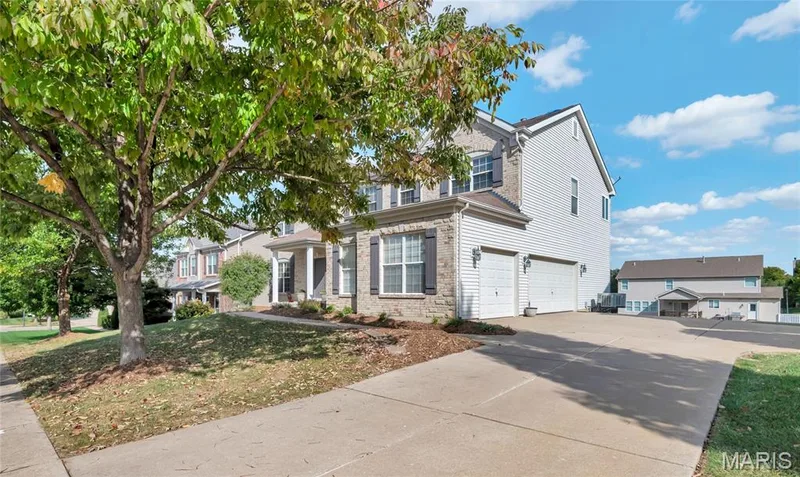Two-story exterior featuring stone veneer and lap siding, a concrete driveway, a three-car garage, and shutter-framed windows — 2061 Avalon Mist Circle, Dardenne Prairie, MO 63368