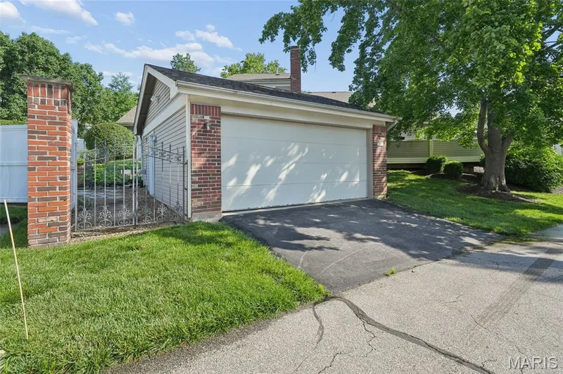 Attached garage with a white panel door, brick facade, and siding accents — 15826 Harris Ridge Court #15826, Chesterfield, MO 63017