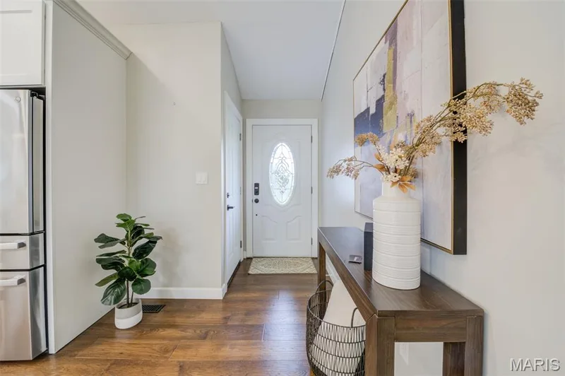 Entryway featuring wood-finish flooring, a white paneled door with an oval glass insert, and light-toned walls — 1094 Harness Drive, St Charles, MO 63304