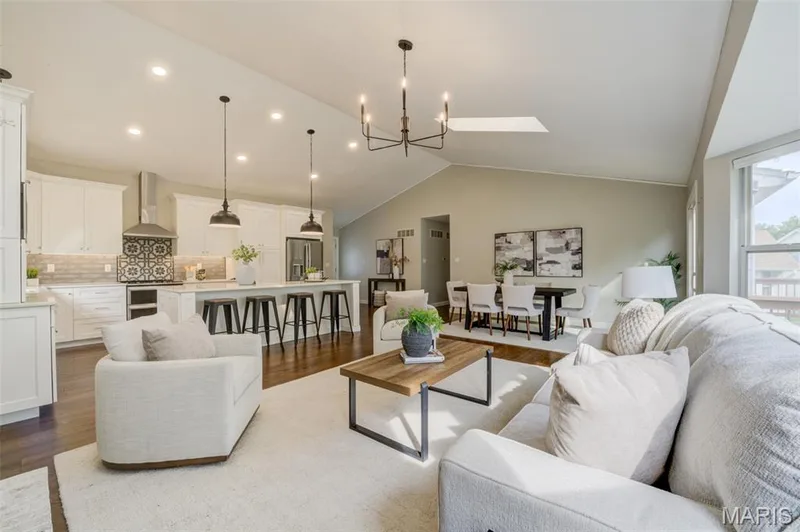 Spacious open-concept living area featuring a vaulted ceiling and rich wood-finish flooring — 1094 Harness Drive, St Charles, MO 63304