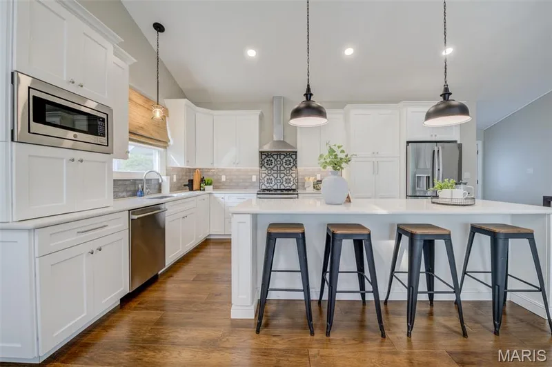 White shaker cabinetry, stainless steel appliances, solid surface countertops, wood-finish flooring, and recessed lighting — 1094 Harness Drive, St Charles, MO 63304