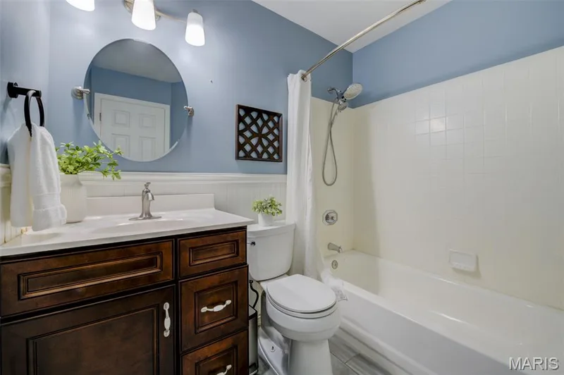 Dark wood-finish vanity with a light-toned countertop, complete with an undermount sink and brushed nickel faucet — 1094 Harness Drive, St Charles, MO 63304