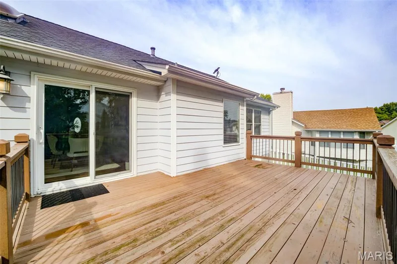 Expansive outdoor deck featuring wood-finish flooring, full railing, siding exterior, and sliding glass door — 1094 Harness Drive, St Charles, MO 63304
