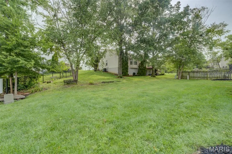 Expansive grassy lawn with mature trees and a partial wood fence — 1094 Harness Drive, St Charles, MO 63304