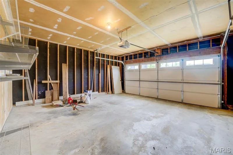 Garage with a concrete floor, exposed wall studs, and an overhead garage door opener — 1094 Harness Drive, St Charles, MO 63304
