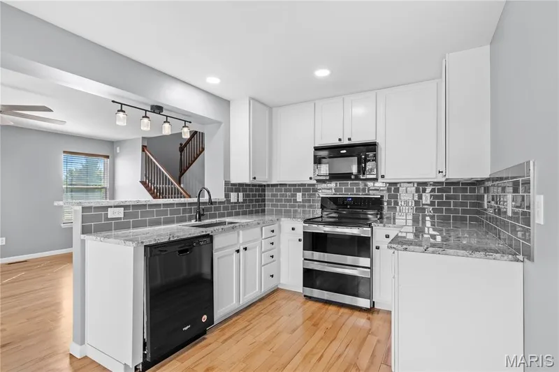 The updated Kitchen features granite counters, beautiful backsplash, stainless steel & black appliances & stunning white cabinets! — 819 Country Field Drive, Lake St. Louis, MO 63367
